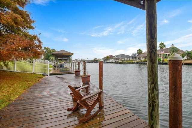 view of dock with a water view, fence, and a gazebo