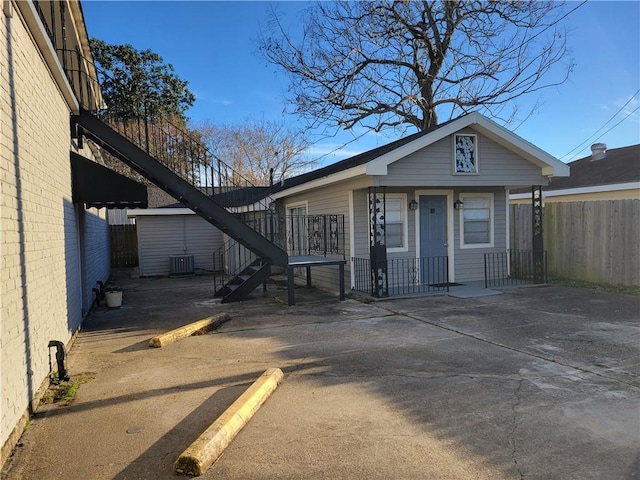 view of front of home featuring cooling unit, stairs, and fence