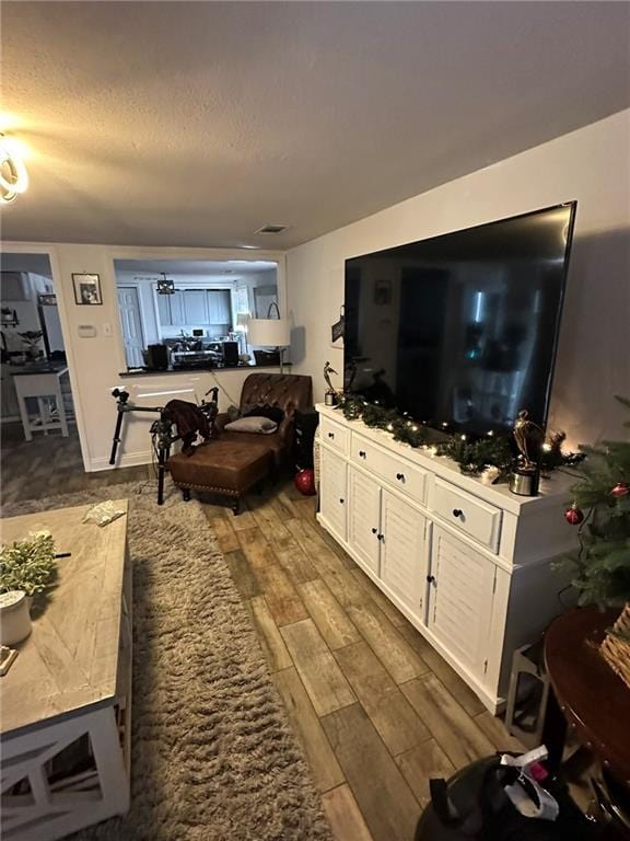 living area featuring visible vents, a textured ceiling, and wood finished floors