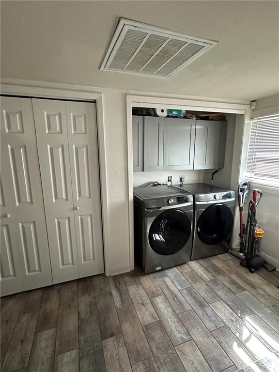 washroom featuring light wood-type flooring, visible vents, cabinet space, and washing machine and dryer