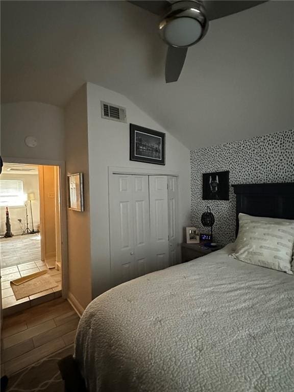 bedroom with visible vents, a ceiling fan, wood finished floors, a closet, and vaulted ceiling