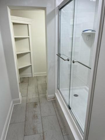 full bath with wood finish floors, baseboards, and a shower stall