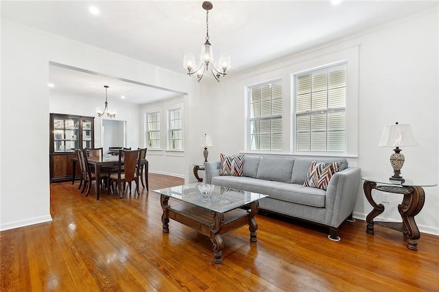 living room with an inviting chandelier, crown molding, baseboards, and hardwood / wood-style flooring