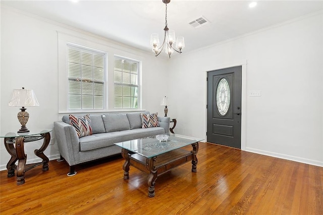 living room featuring a chandelier, visible vents, crown molding, and wood finished floors