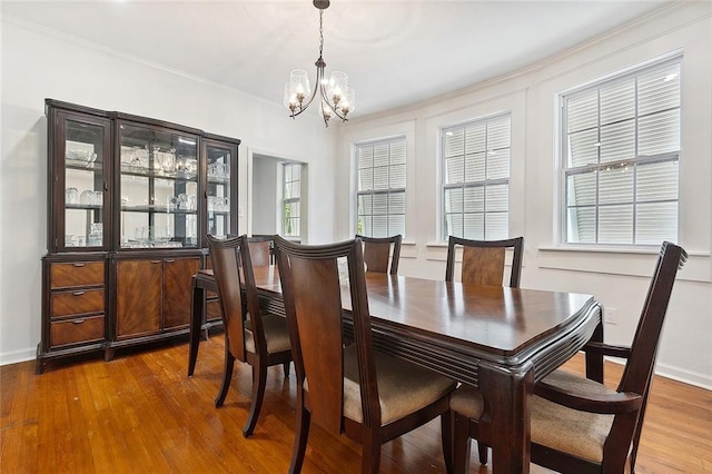 dining area with baseboards, an inviting chandelier, and wood finished floors