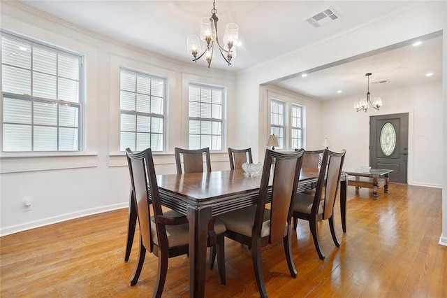 dining room featuring a chandelier, visible vents, baseboards, light wood-type flooring, and crown molding