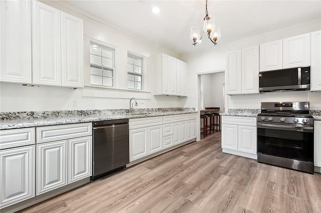 kitchen with stainless steel appliances, light wood-type flooring, a sink, and white cabinetry