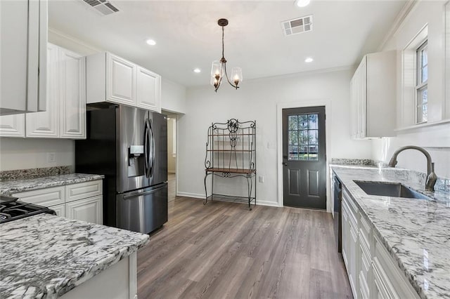 kitchen featuring appliances with stainless steel finishes, a sink, visible vents, and white cabinets