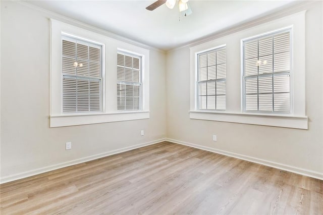 empty room with a ceiling fan, crown molding, baseboards, and wood finished floors