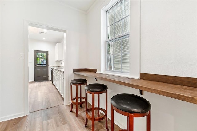 interior space featuring baseboards, ornamental molding, visible vents, and light wood-style floors