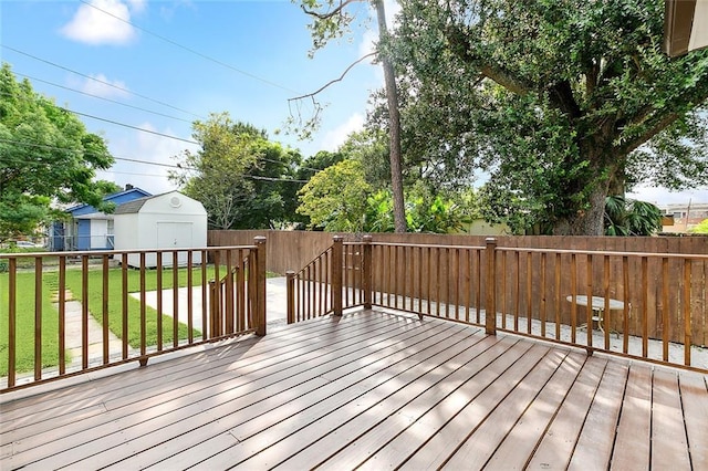 deck with a fenced backyard, a yard, an outdoor structure, and a shed