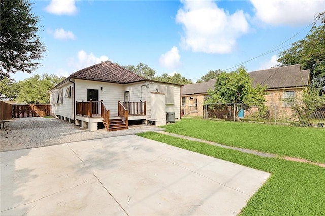 back of property with a fenced backyard, driveway, a lawn, a wooden deck, and a patio area