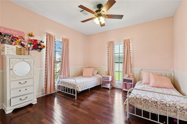 bedroom with wood-type flooring, multiple windows, ceiling fan, and visible vents