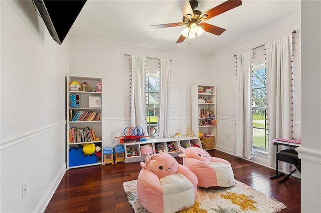 recreation room featuring a healthy amount of sunlight, hardwood / wood-style flooring, baseboards, and a ceiling fan