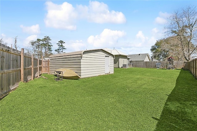 view of yard featuring an outbuilding, a fenced backyard, a playground, and a storage unit