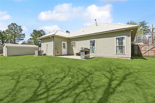 back of property with metal roof, a lawn, cooling unit, and fence