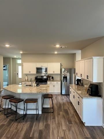 kitchen featuring appliances with stainless steel finishes, a kitchen breakfast bar, and dark wood-style floors