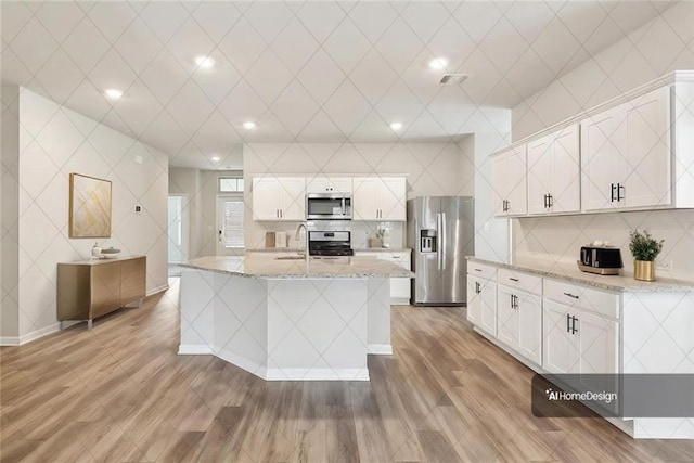 5635 Oak Trace Dr, Saint Gabriel, LA 70776 - kitchen with stainless steel appliances, light wood-style floors, a sink, backsplash, and white cabinetry