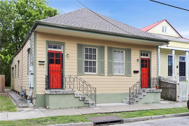 view of front of house featuring roof with shingles and fence