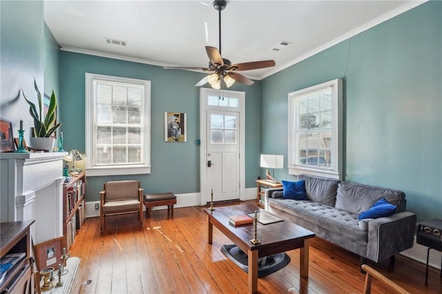 living area featuring visible vents, crown molding, and light wood finished floors