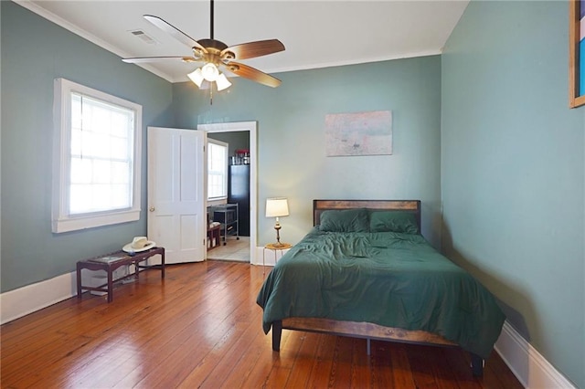 bedroom with baseboards, wood-type flooring, visible vents, and crown molding