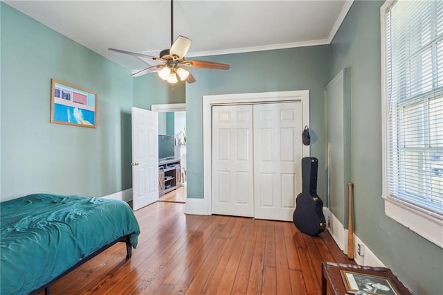 bedroom featuring ceiling fan, baseboards, a closet, hardwood / wood-style floors, and crown molding