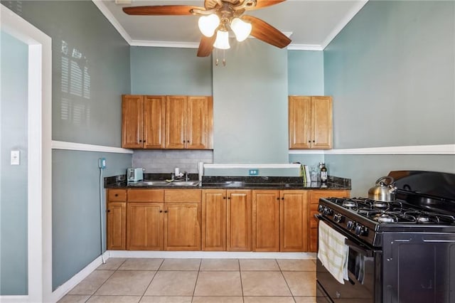 kitchen with light tile patterned floors, backsplash, ornamental molding, black gas stove, and dark stone countertops