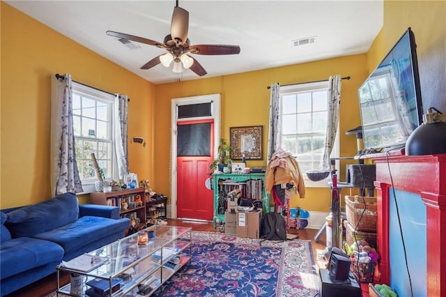 interior space with a ceiling fan, wood finished floors, visible vents, and a healthy amount of sunlight