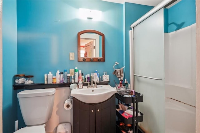 full bath featuring toilet, vanity, and a shower with shower door