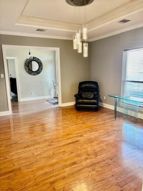 unfurnished room featuring light wood-type flooring, baseboards, and a tray ceiling