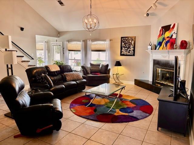 209 Legrande Bayou Ln, Kenner, LA 70065 - living area with tile patterned flooring, a fireplace, visible vents, vaulted ceiling, and rail lighting