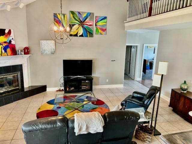209 Legrande Bayou Ln, Kenner, LA 70065 - tiled living room featuring a high ceiling, an inviting chandelier, a tile fireplace, and baseboards