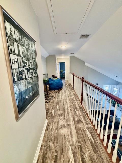 209 Legrande Bayou Ln, Kenner, LA 70065 - hallway with lofted ceiling, wood finished floors, visible vents, baseboards, and attic access
