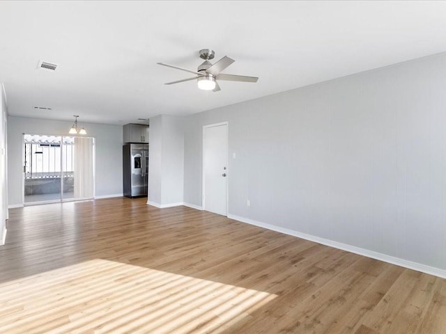 unfurnished living room featuring light wood-style floors, visible vents, baseboards, and ceiling fan with notable chandelier