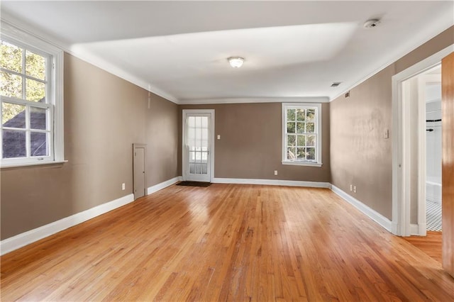 spare room featuring baseboards, light wood-type flooring, and crown molding