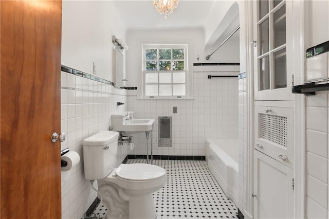 full bath featuring tile walls, wainscoting, toilet, a sink, and shower / bathing tub combination