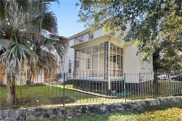 view of front of home with a sunroom, fence, and a front lawn