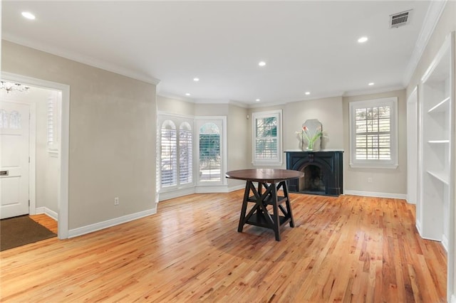 dining area with light wood finished floors, baseboards, a fireplace, and visible vents