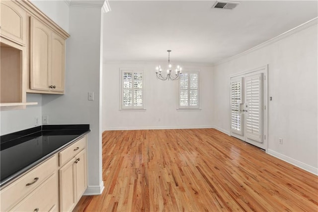 kitchen with light wood-type flooring, dark countertops, visible vents, and crown molding