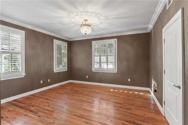 spare room featuring ornamental molding, light wood finished floors, plenty of natural light, and baseboards