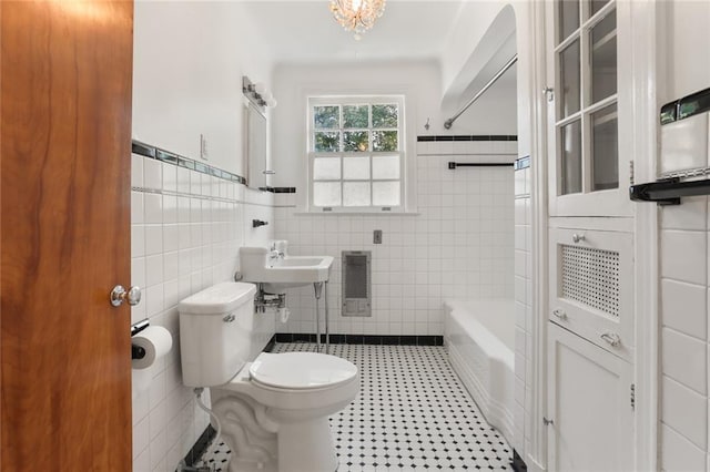 full bathroom with tile patterned flooring, toilet, a wainscoted wall, a sink, and tile walls