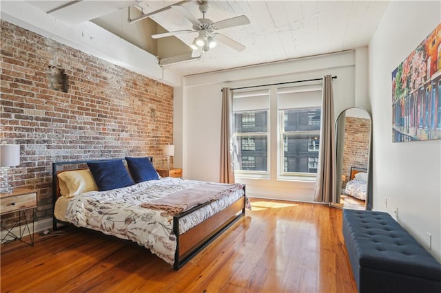 bedroom with a ceiling fan, wood-type flooring, and brick wall