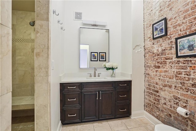 bathroom featuring brick wall, baseboards, walk in shower, and vanity