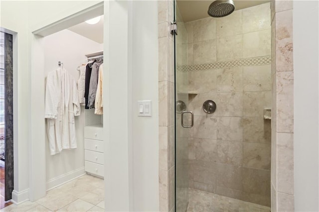 full bathroom featuring a stall shower, a spacious closet, and baseboards