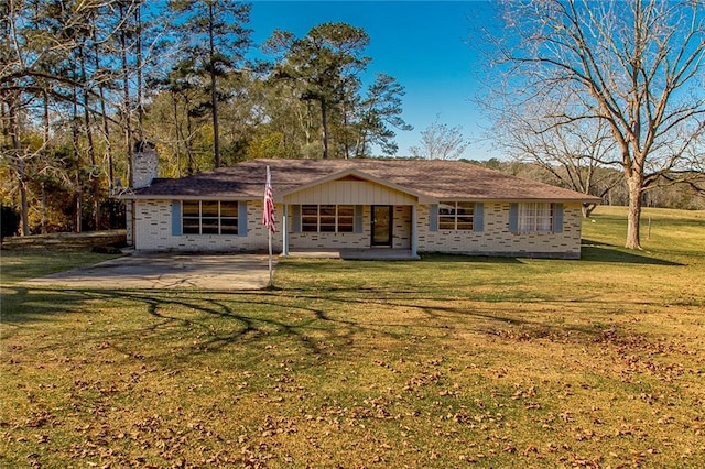 rear view of property featuring a chimney, a lawn, and brick siding