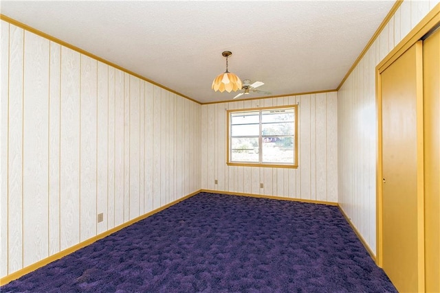 carpeted spare room with ceiling fan, a textured ceiling, ornamental molding, and baseboards