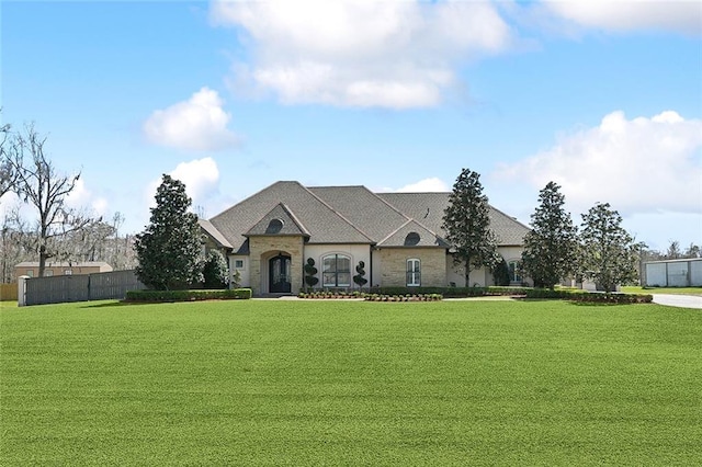 french country style house featuring fence and a front lawn