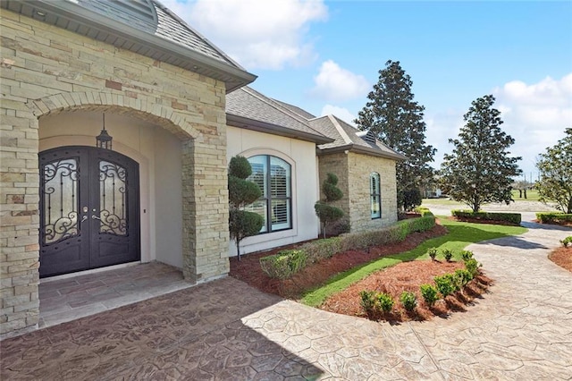 entrance to property with a shingled roof and french doors