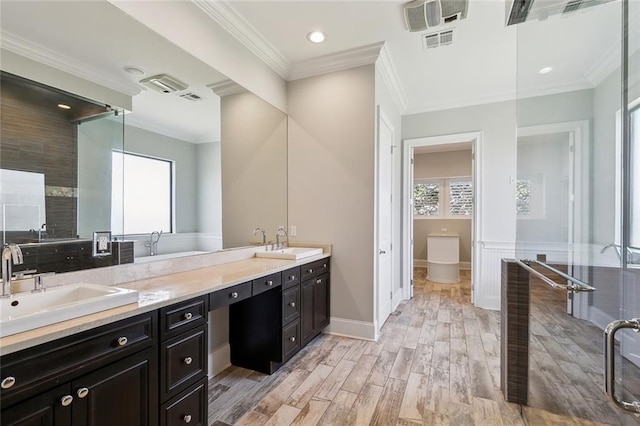 bathroom with crown molding, double vanity, a sink, and wood finished floors