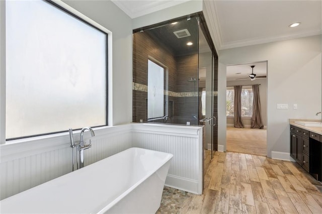 bathroom with a wainscoted wall, crown molding, a freestanding bath, and wood finished floors